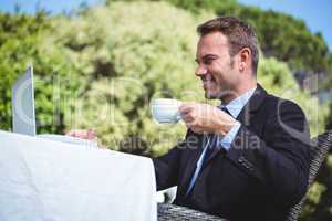 Businessman using laptop and having a coffee