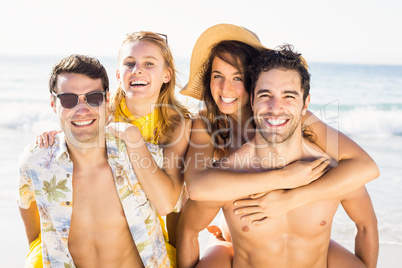 Portrait of men giving a piggy back to women on the beach