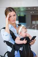 Tensed woman with mobile phone carrying baby girl