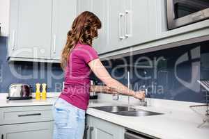 Woman filling water in glass at kitchen counter