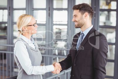 Business people handshaking while standing in office