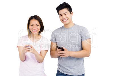 Cheerful young couple text messaging on mobile phone