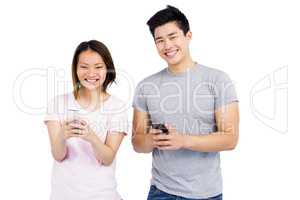 Cheerful young couple text messaging on mobile phone