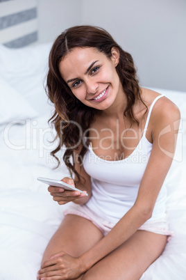 Portrait of pretty woman using mobile phone on bed