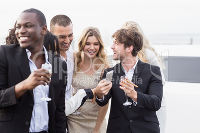 Well dressed people looking smartphone next to a limousine