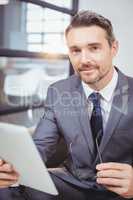 Portrait of confident businessman holding digital tablet while s