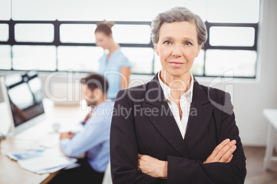 Confident businesswoman with colleague working in background