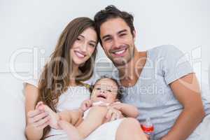 Happy couple with baby relaxing on bed