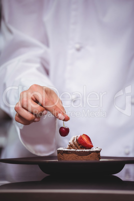 Chef putting a cherry on a dessert