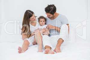 Parents with child sitting on bed
