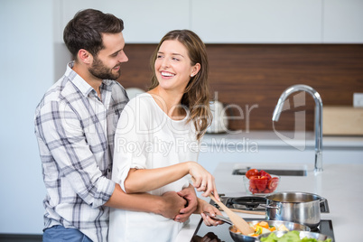 Happy man embracing woman while cooking food