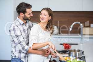 Happy man embracing woman while cooking food
