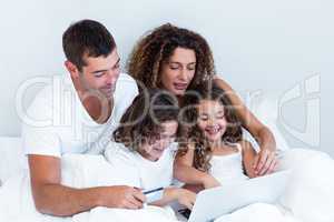 Family with credit card shopping online on bed