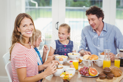 Happy mother having breakfast with family at table