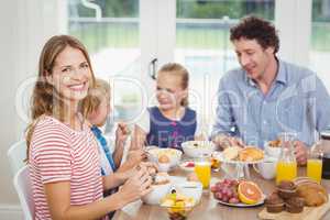 Happy mother having breakfast with family at table