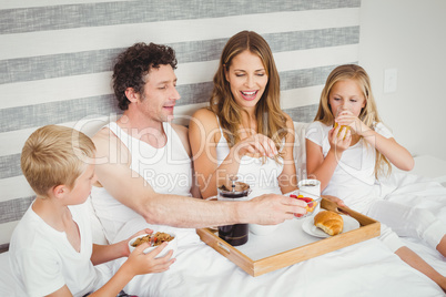 Family enjoying breakfast on bed