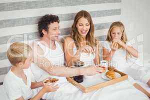 Family enjoying breakfast on bed