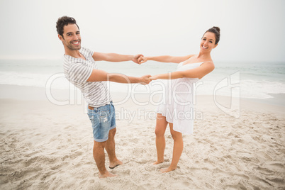 Happy couple holding hands on the beach