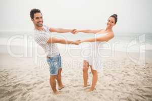 Happy couple holding hands on the beach
