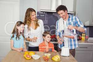 Father pouring fruit juice in glass with family