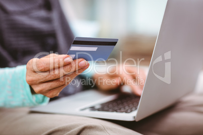 Woman holding credit card while using laptop