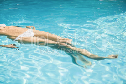 Woman in white bikini floating in swimming pool