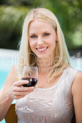 Smiling young woman holding red wine glass