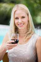 Smiling young woman holding red wine glass