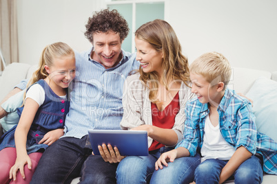 Family using digital tablet while sitting on sofa