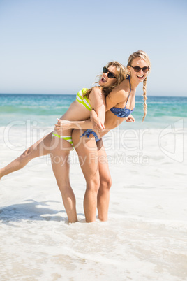 Two happy women in bikini and sunglasses having fun on the beach