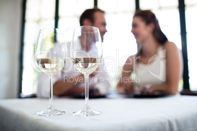 Close up of two wine glasses and couple in background