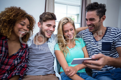 Young friends looking in mobile phone while sitting on sofa
