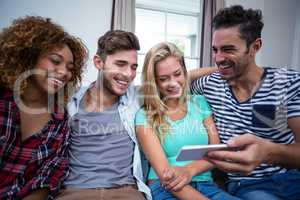 Young friends looking in mobile phone while sitting on sofa