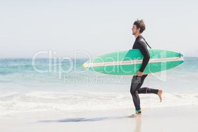 Man with surfboard running towards sea