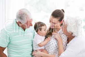 Smiling grandparents and mother playing with baby