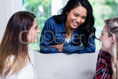 Beautiful young female friends discussing in living room