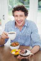 Happy man drinking tea by table