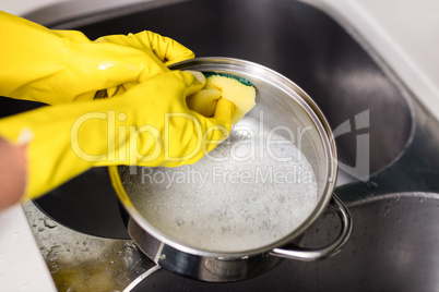 Woman wearing gloves washing utensils at home