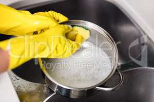 Woman wearing gloves washing utensils at home