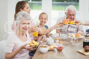 Happy multi-generation family eating fruits during breakfast