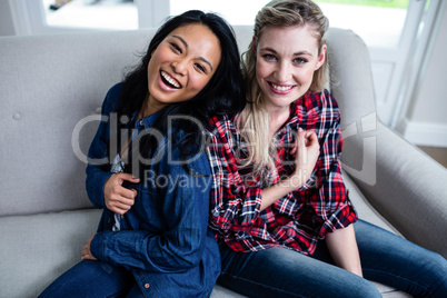 Happy young beautiful friends sitting on sofa