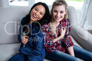 Happy young beautiful friends sitting on sofa