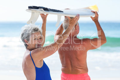 Cute mature couple holding a surfboard