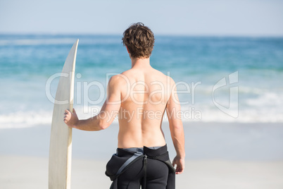 Rear view of man with surfboard standing on the beach