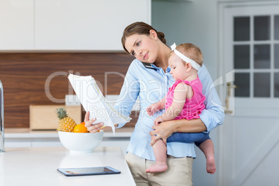 Woman reading documents while carrying baby girl