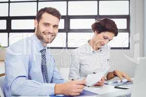 Businessman with document while female colleague sitting beside