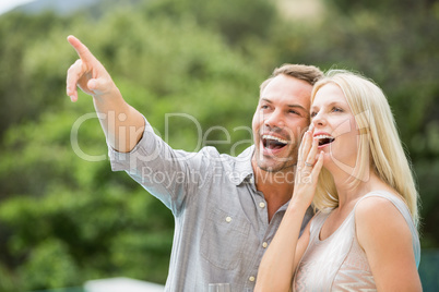 Smiling man pointing while standing by surprised woman