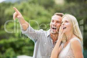 Smiling man pointing while standing by surprised woman