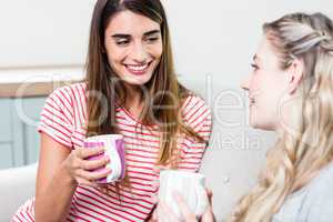 Beautiful female friends smiling while drinking coffee
