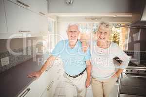 Portrait of happy senior couple standing in kitchen